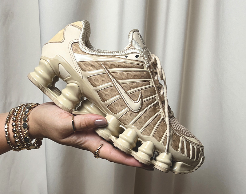 Tênis Nike Shox na cor bege, foco na sola e design inovador.